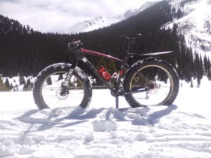 A fat tire bike parked in the winter snow.