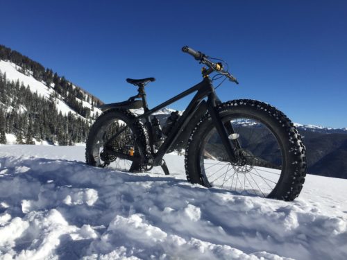 A fat tire bike parked in the winter snow.