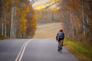 Shoulder Sesason in Mountain Towns - Biking down a mountain road with fall colors