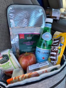 A bag packed with snacks and water for a road trip.
